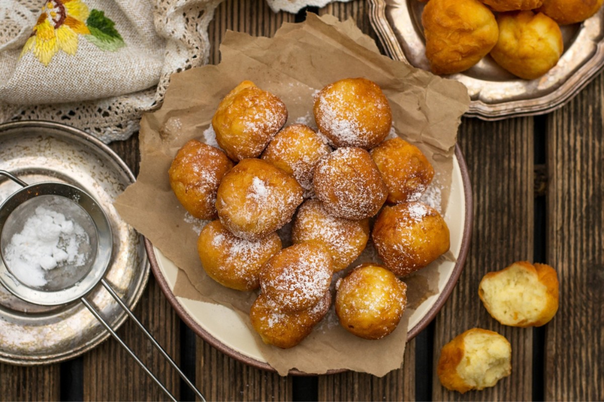 A plate of Fritule with icing sugar sprinkled on top